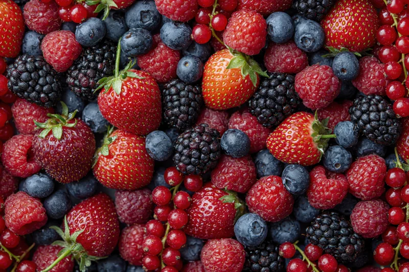 Overhead flat lay of mixed fresh berries densely covering the frame