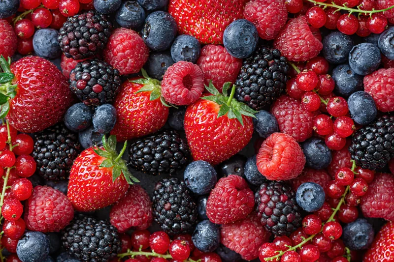 Overhead flat lay of mixed fresh berries densely covering the frame