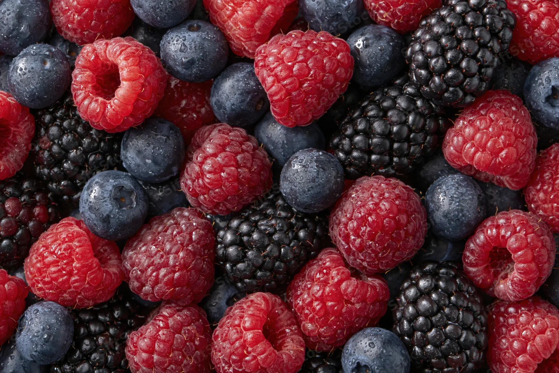 Overhead flat lay of mixed fresh raspberries blueberries and blackberries