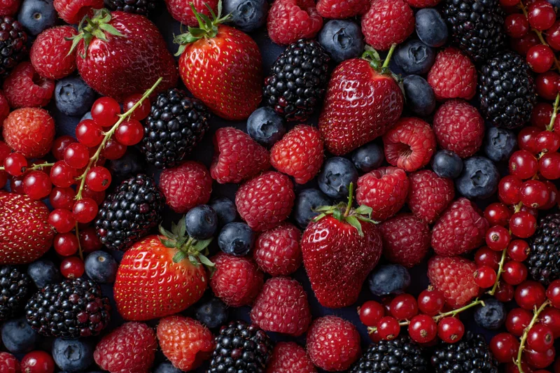 Overhead flat lay of mixed fresh berries including strawberries raspberries blueberries blackberries and redcurrants