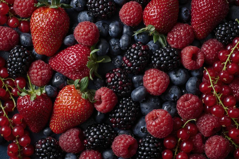 Overhead flat lay of mixed fresh berries including strawberries raspberries blueberries blackberries and redcurrants