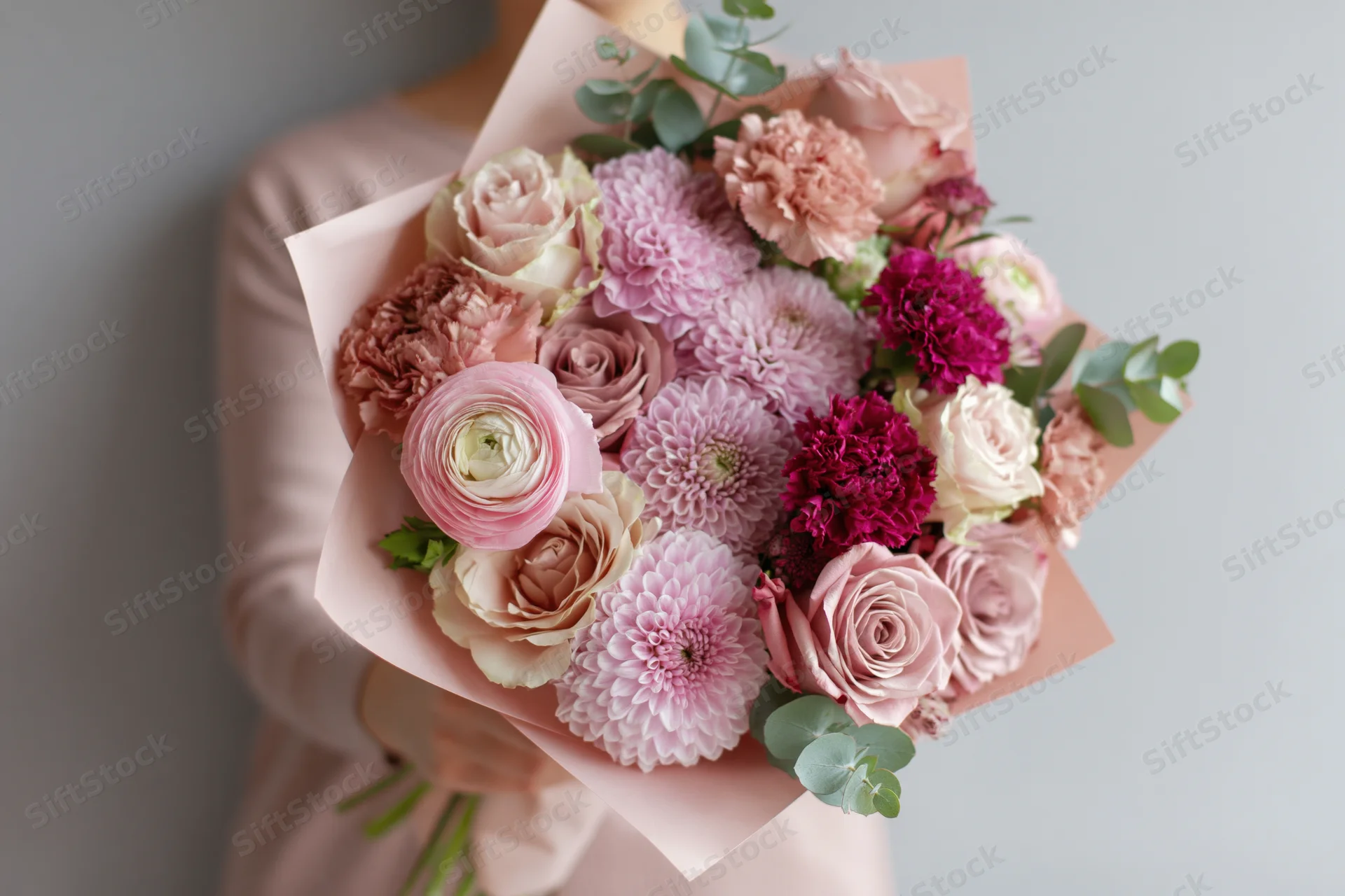 Woman holding a large mixed flower bouquet wrapped in blush paper