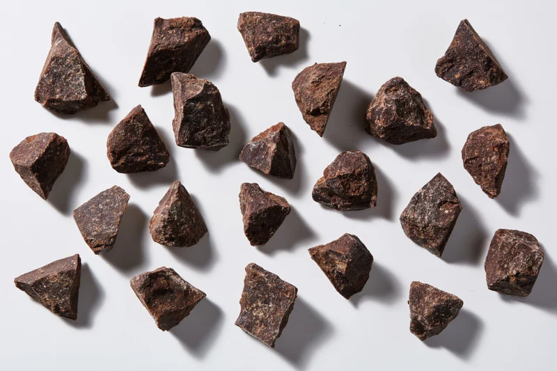Broken dark chocolate chunks scattered across a white surface in a flat lay arrangement