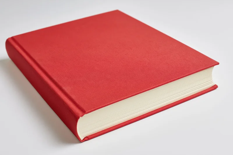 Red hardcover book closed on white surface
