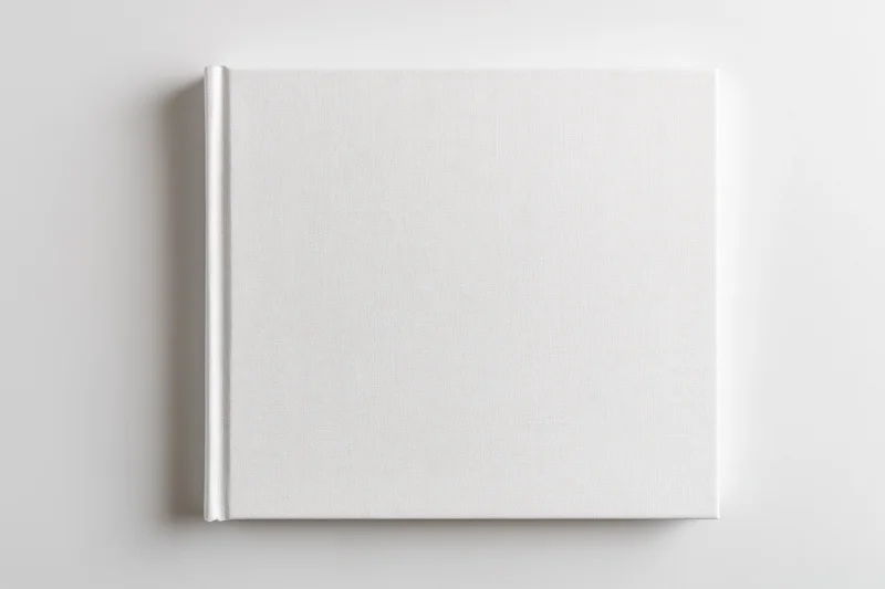 Square hardcover book with blank white cover lying flat on white surface