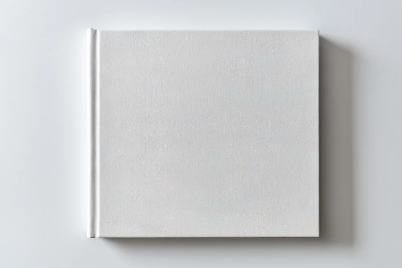 Square hardcover book with blank white cover on plain surface