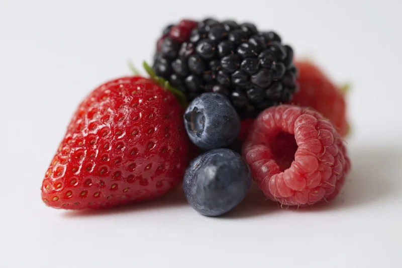 Mixed fresh berries arranged on a white surface