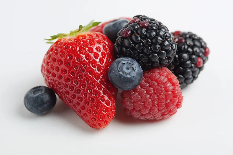 Mixed fresh berries arranged on a white background