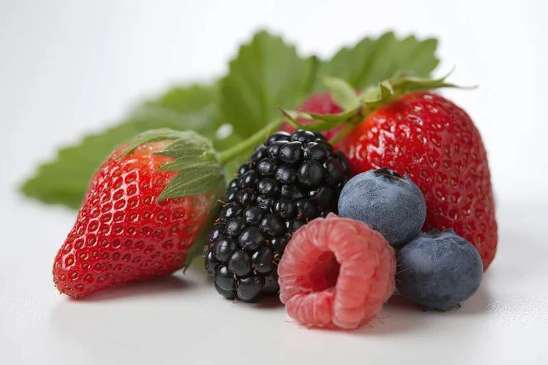 Mixed fresh berries arranged on a white surface