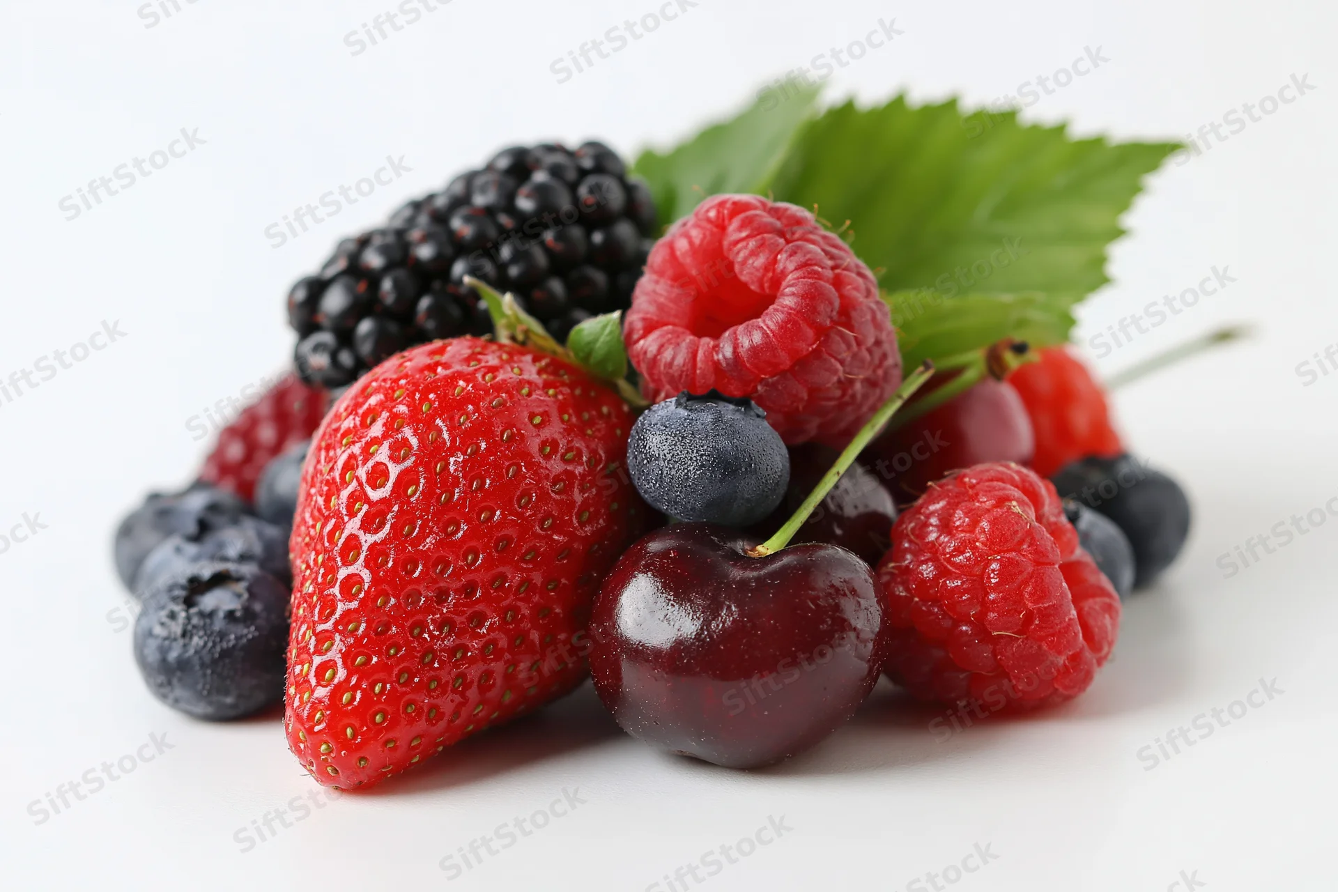Mixed fresh berries arranged in a cluster on white background