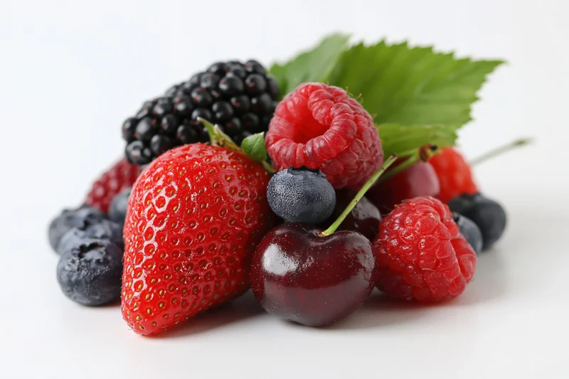 Mixed fresh berries arranged in a cluster on white background