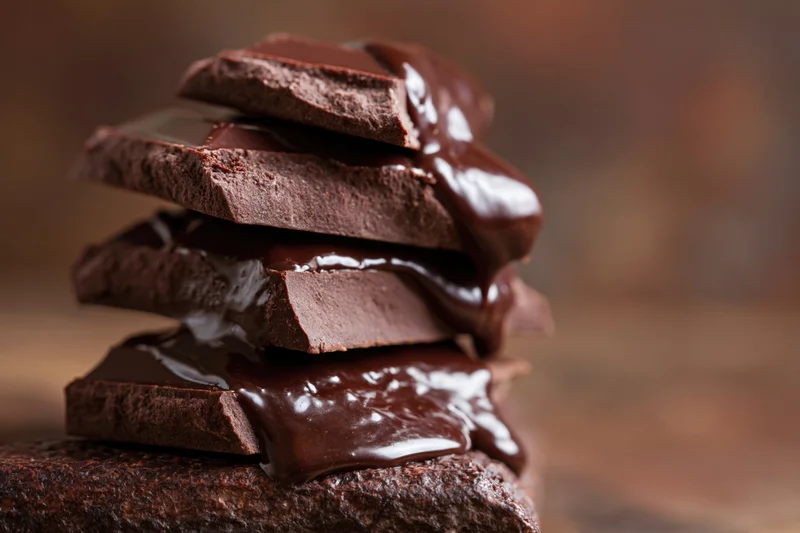 Stacked broken chocolate pieces with melted chocolate dripping