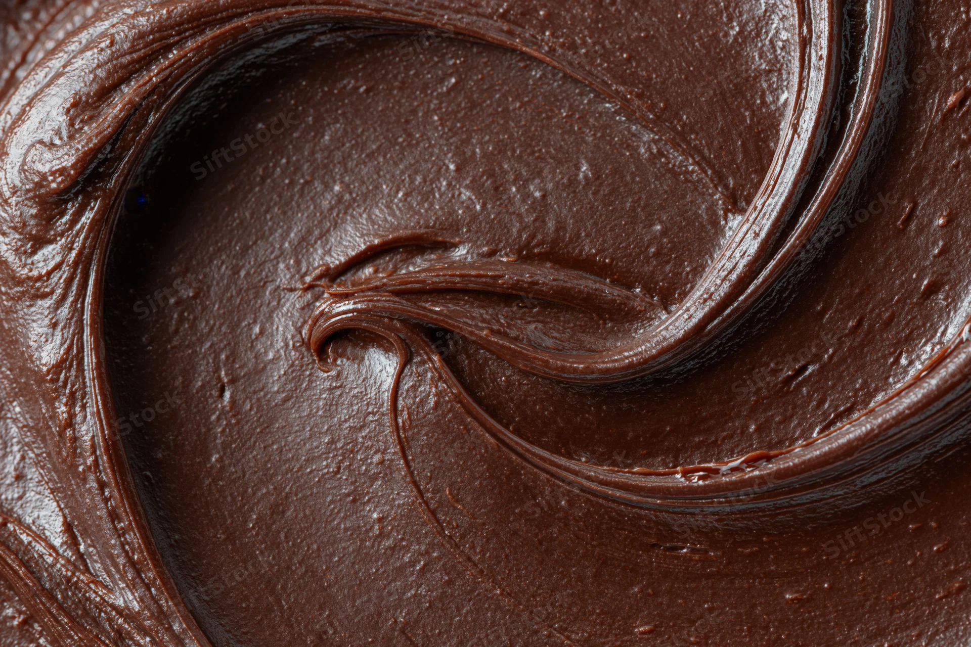 Thick dark chocolate ganache swirled in a glossy pattern closeup