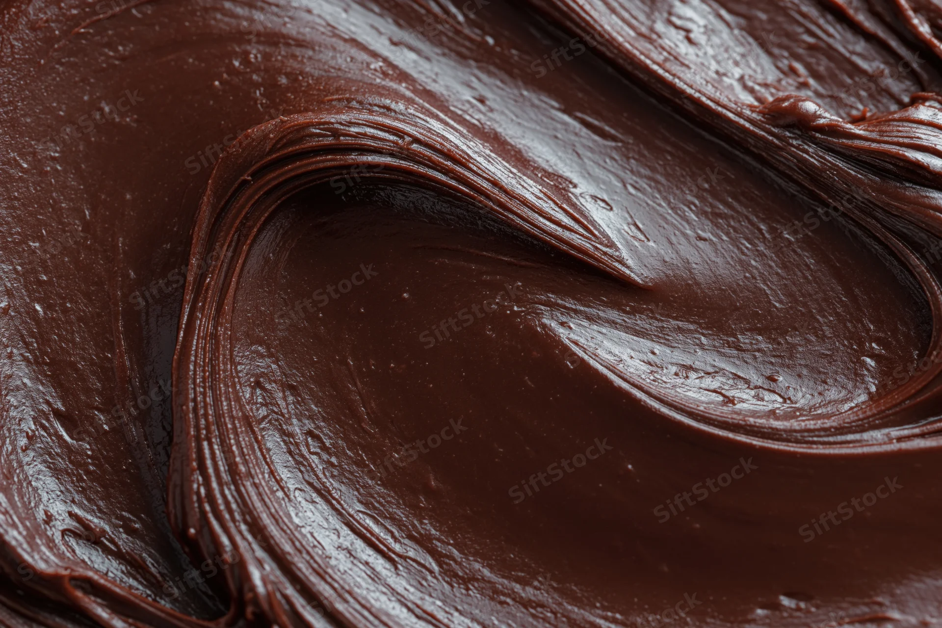Thick dark chocolate ganache spread in sweeping swirl pattern closeup