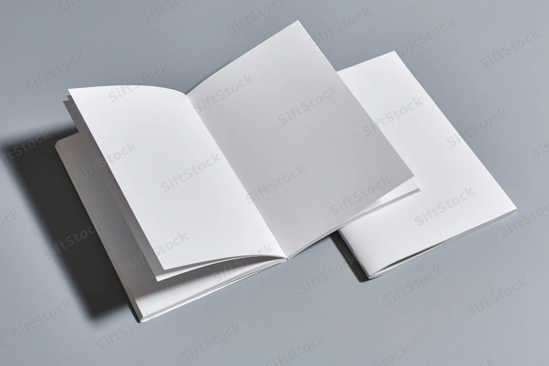 Two blank white magazines one open flat on gray surface