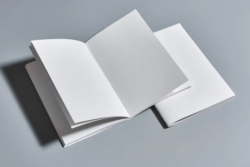 Two blank white magazines one open flat on gray surface