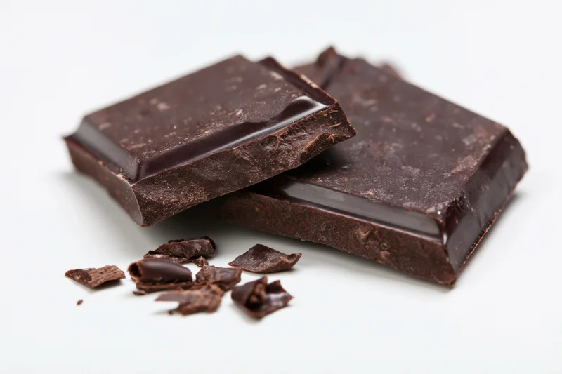 Broken dark chocolate bar pieces resting on white surface