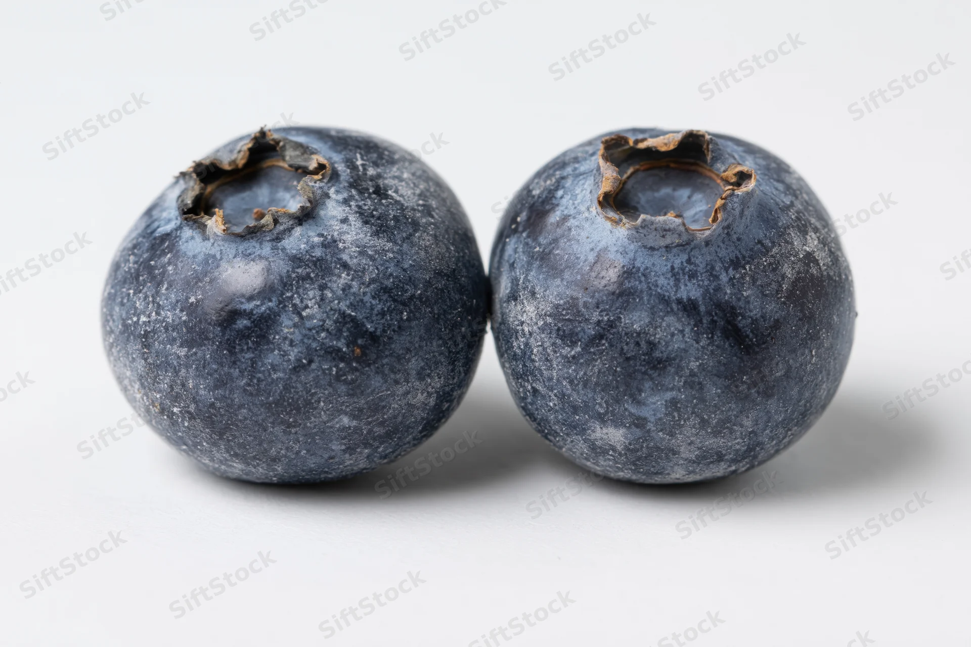 Two fresh blueberries side by side on a white background