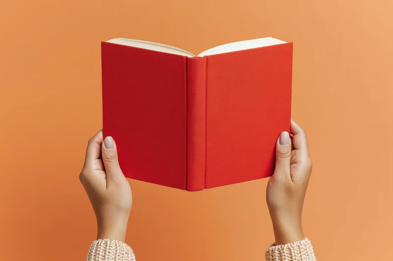 Hands holding open red hardcover book against orange background