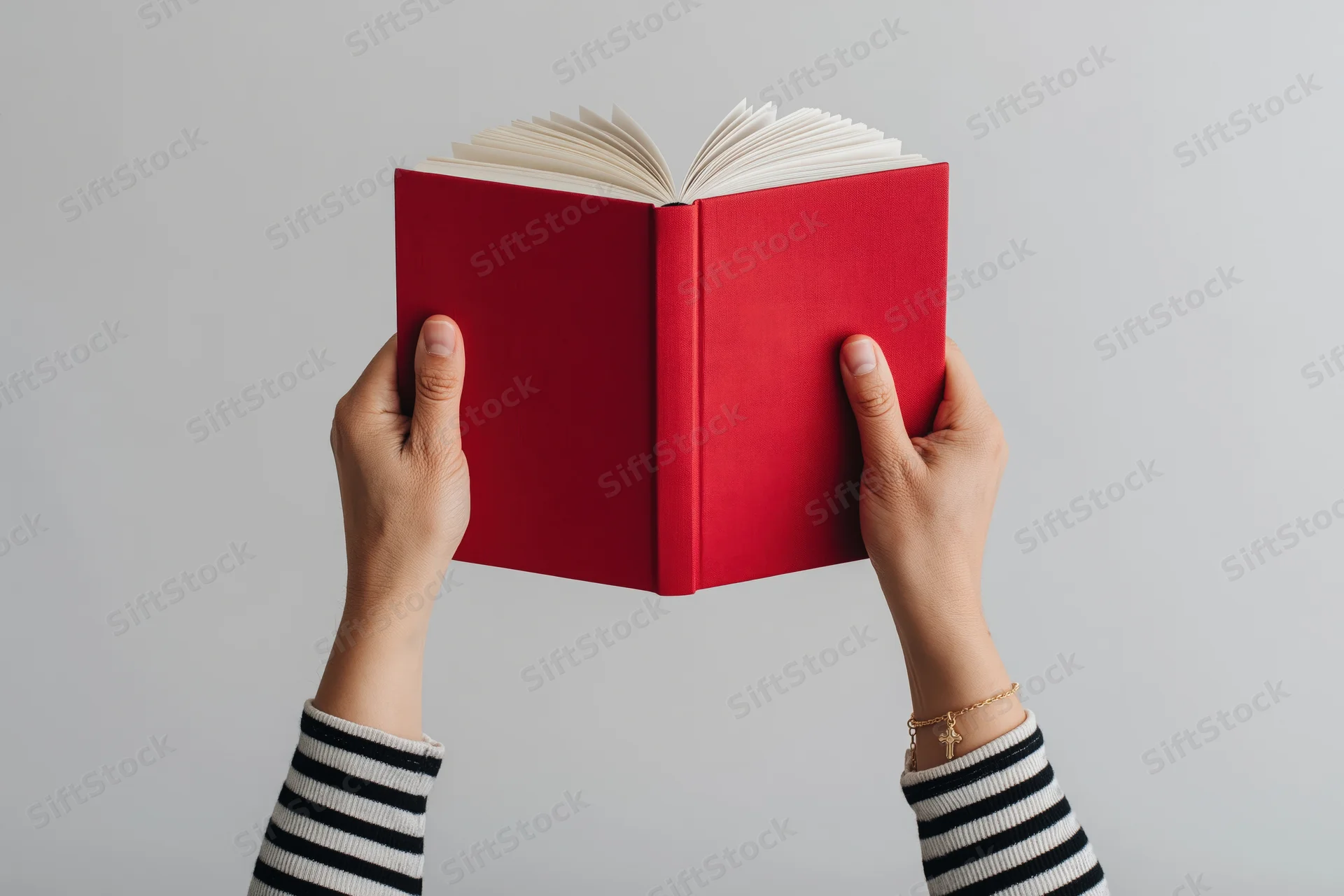 Hands holding open red hardcover book above white background