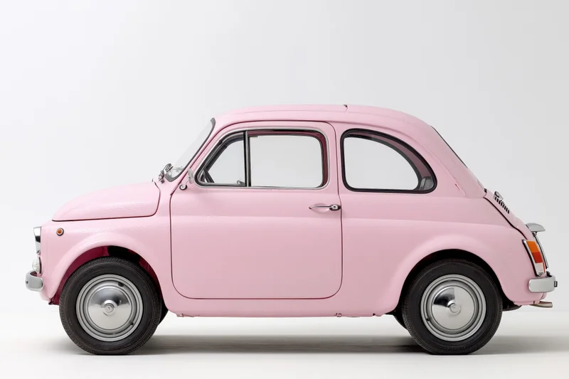 Vintage pink italian compact car side view in studio setting
