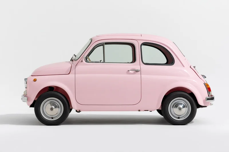 Vintage pink italian compact car shown in side profile against white studio background