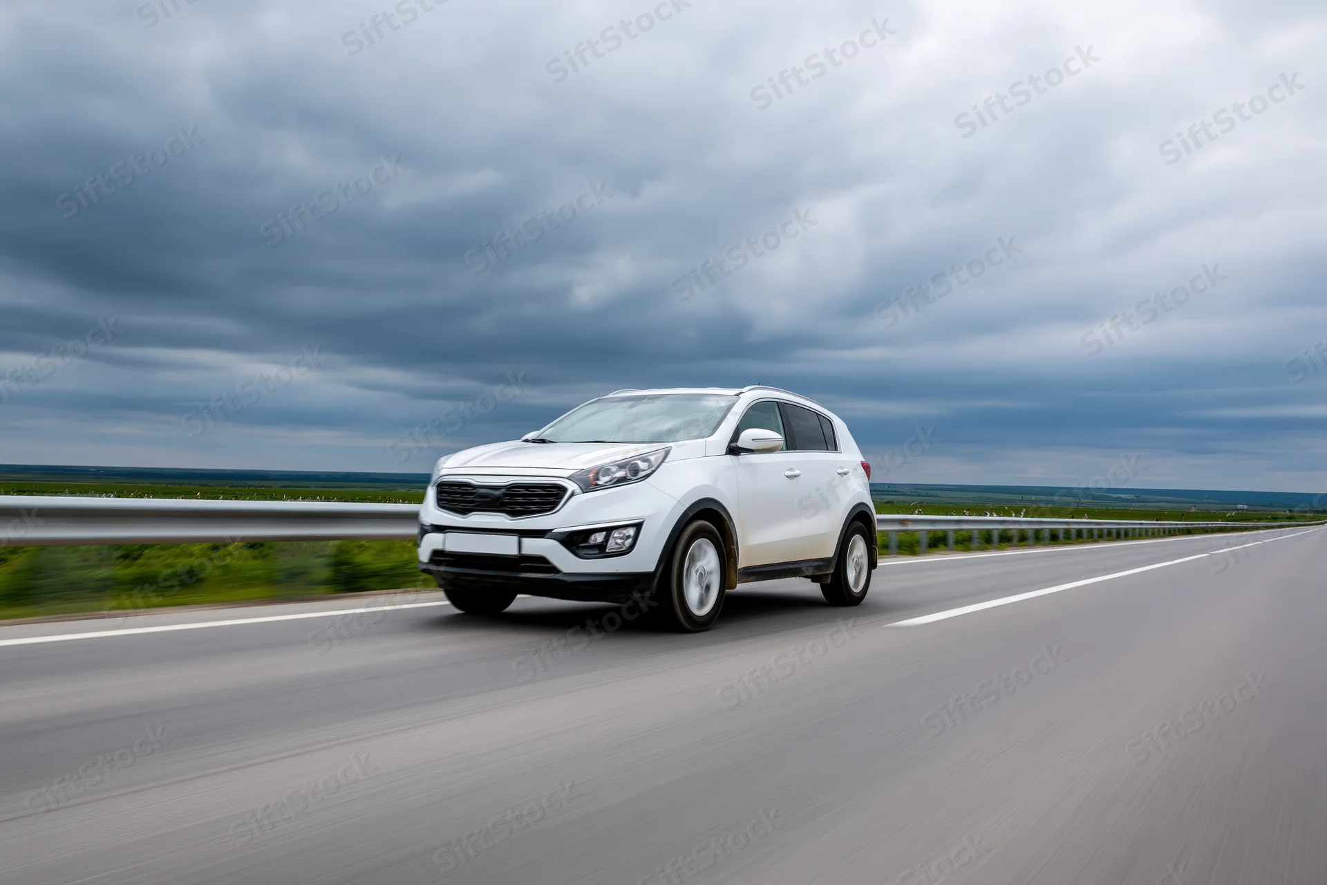 White compact suv driving on a two-lane highway under cloudy sky