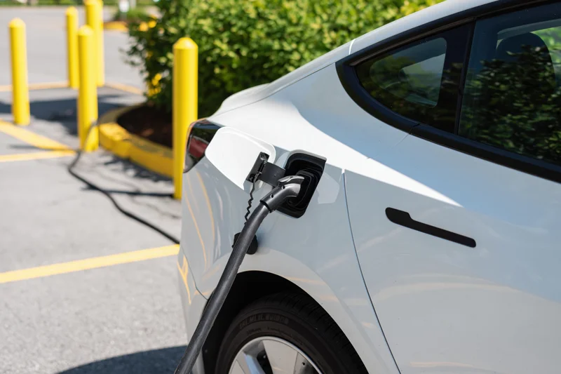 White electric car charging at public station in parking lot