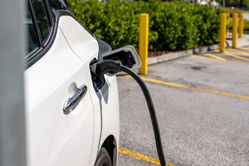 White electric car charging at public station in parking lot