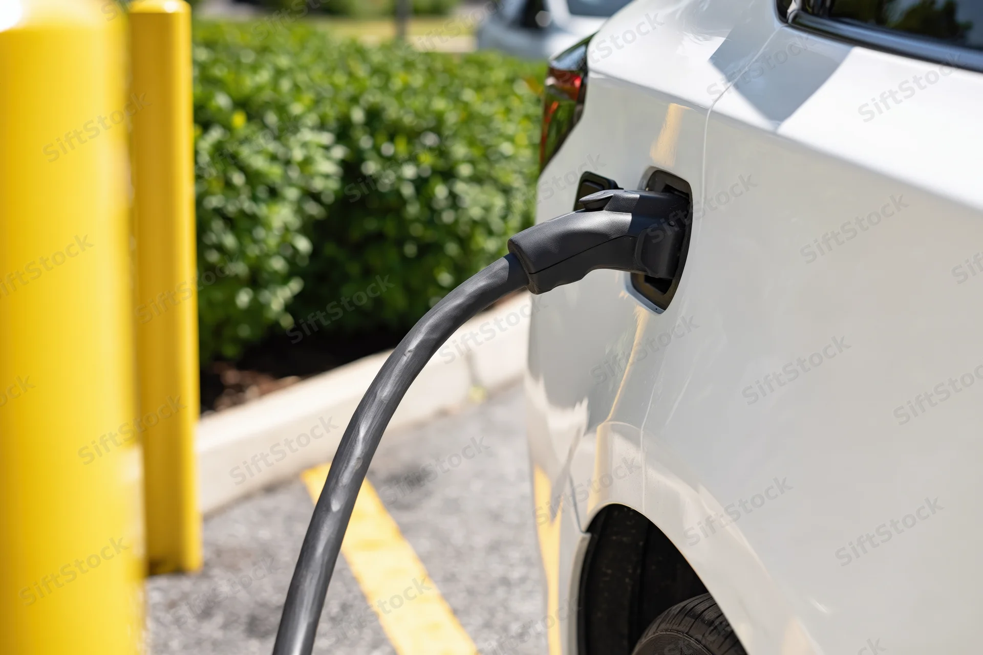 White electric vehicle plugged into public charging station outdoors