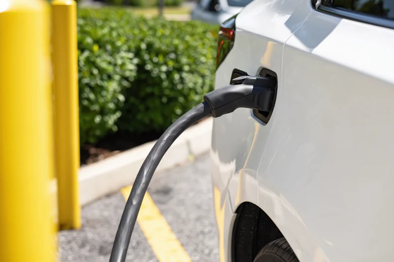 White electric vehicle plugged into public charging station outdoors