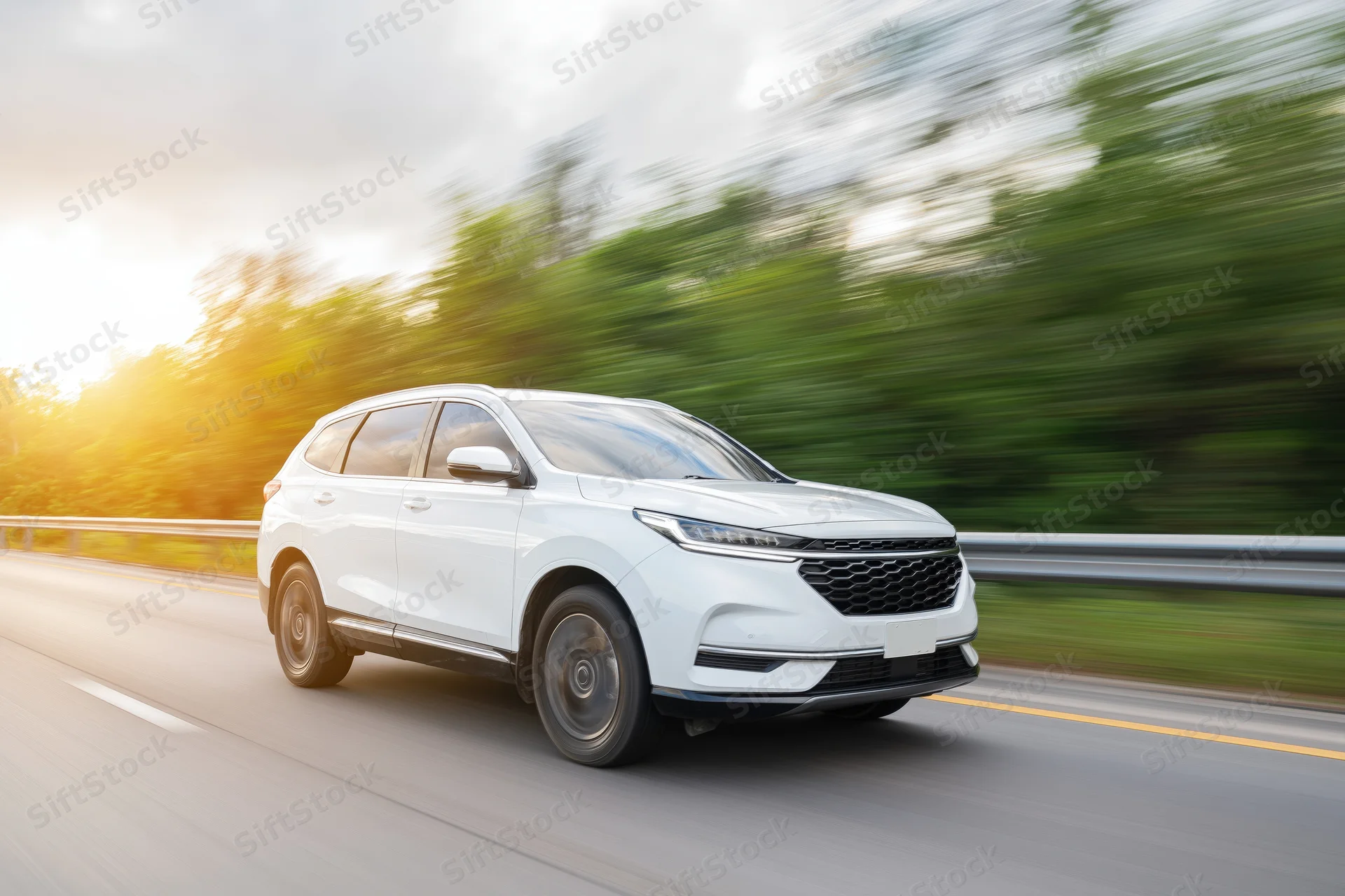 White suv driving on a two-lane highway with motion blur and sunset lighting