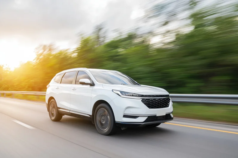 White suv driving on a two-lane highway with motion blur and sunset lighting