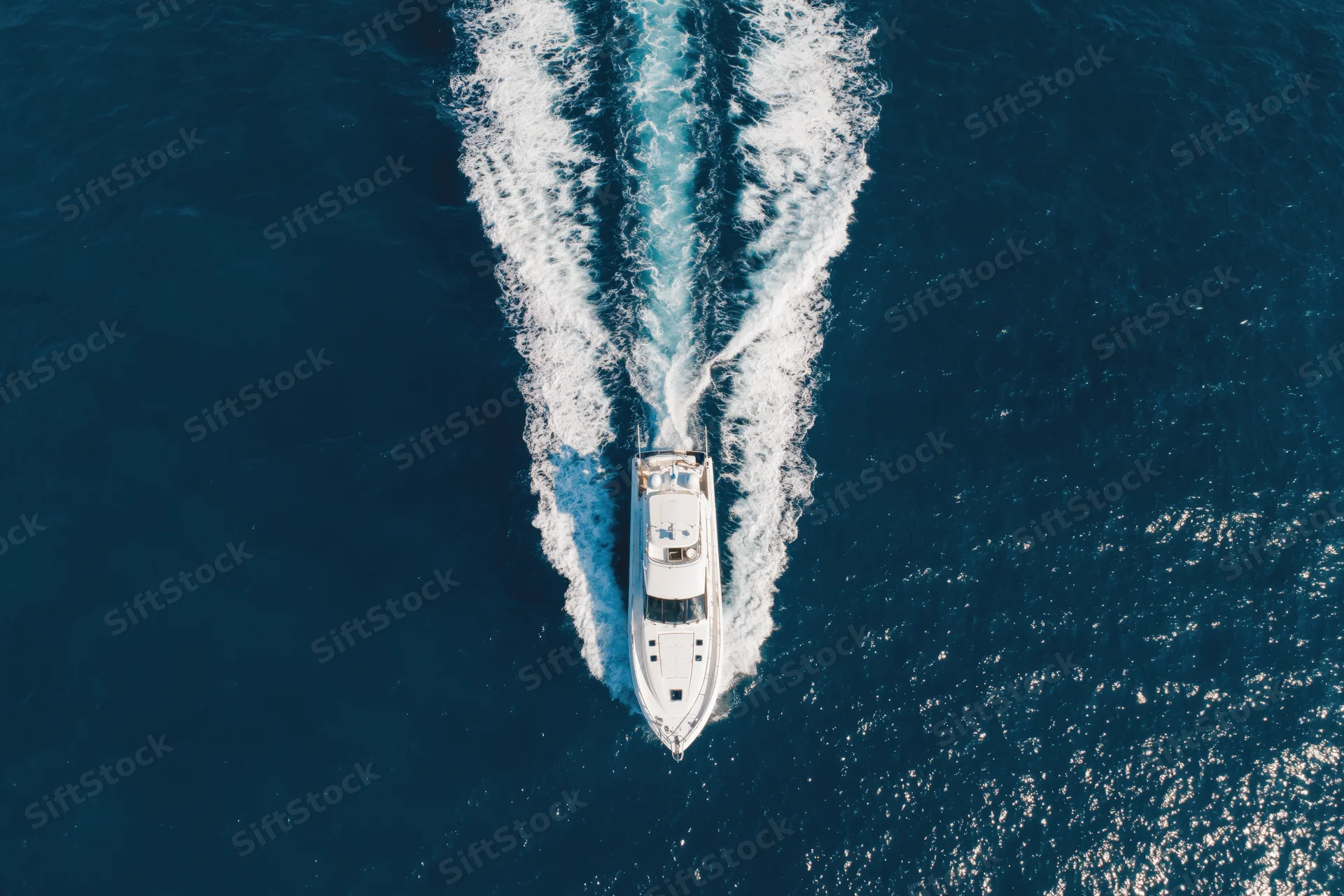 White motor yacht moving through deep blue ocean leaving a foamy wake