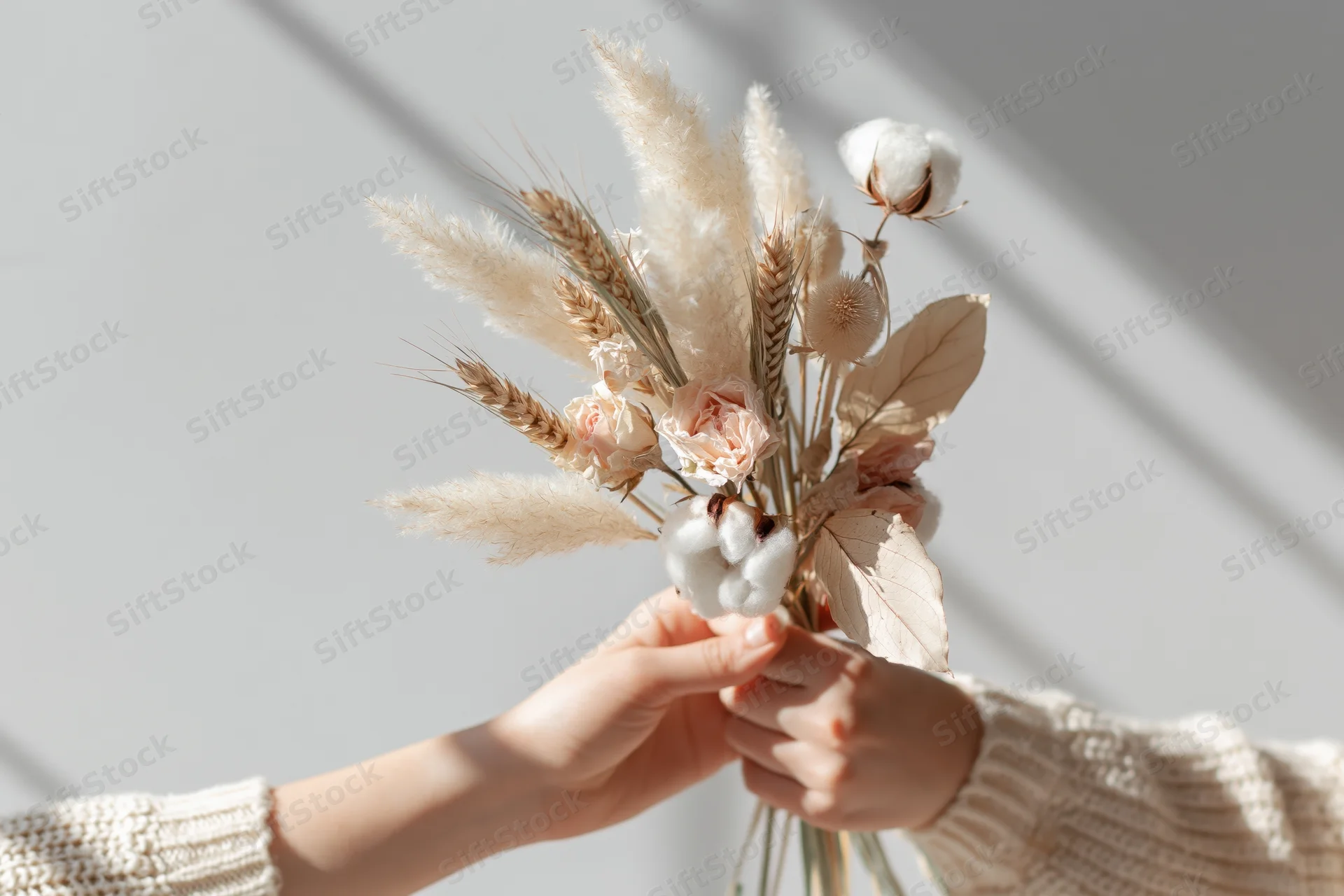 Woman holding a dried flower bouquet with both hands indoors
