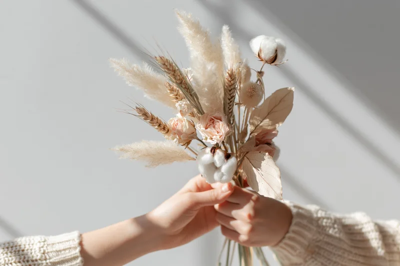 Woman holding a dried flower bouquet with both hands indoors