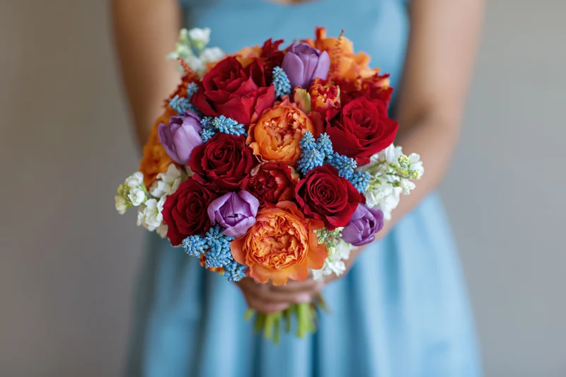 Woman holding a dense mixed flower bouquet in a light blue dress