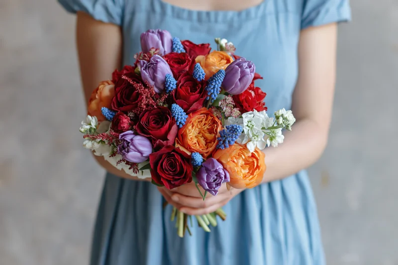 Woman holding a dense mixed flower bouquet in a light blue dress