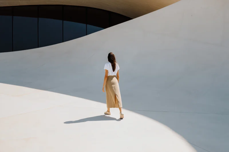 Woman walking away on curved white concrete structure outdoors