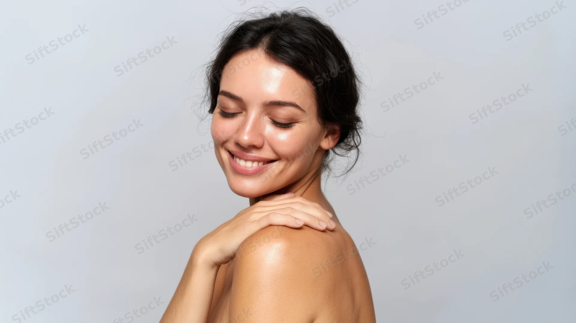 Smiling brunette woman touching her shoulder in a studio portrait