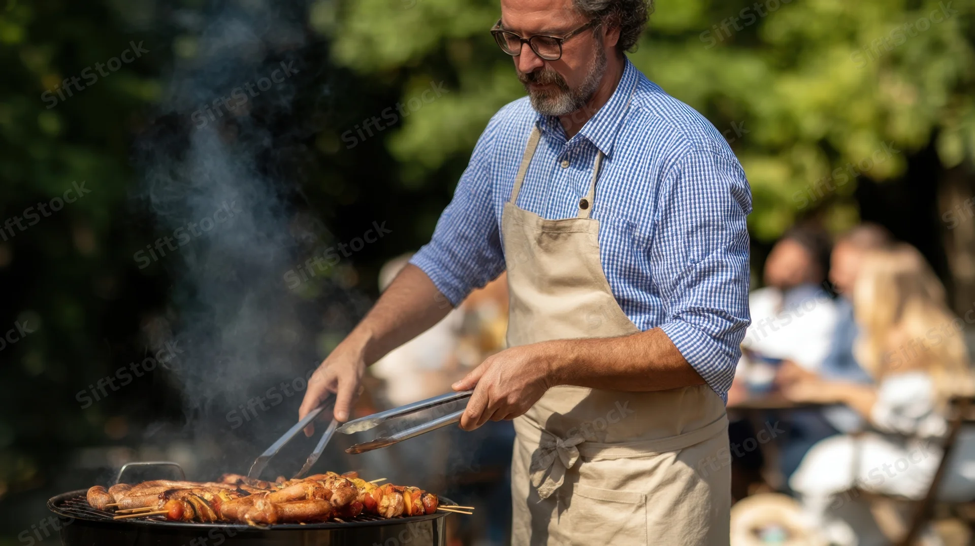 Man grilling sausages and skewers on a charcoal barbecue in a garden setting