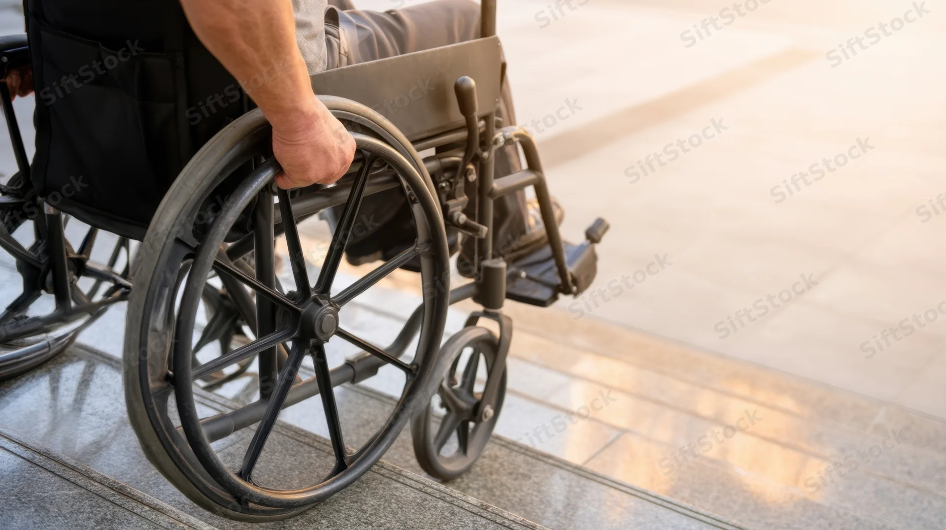 Man in wheelchair propelling himself up a paved incline outdoors