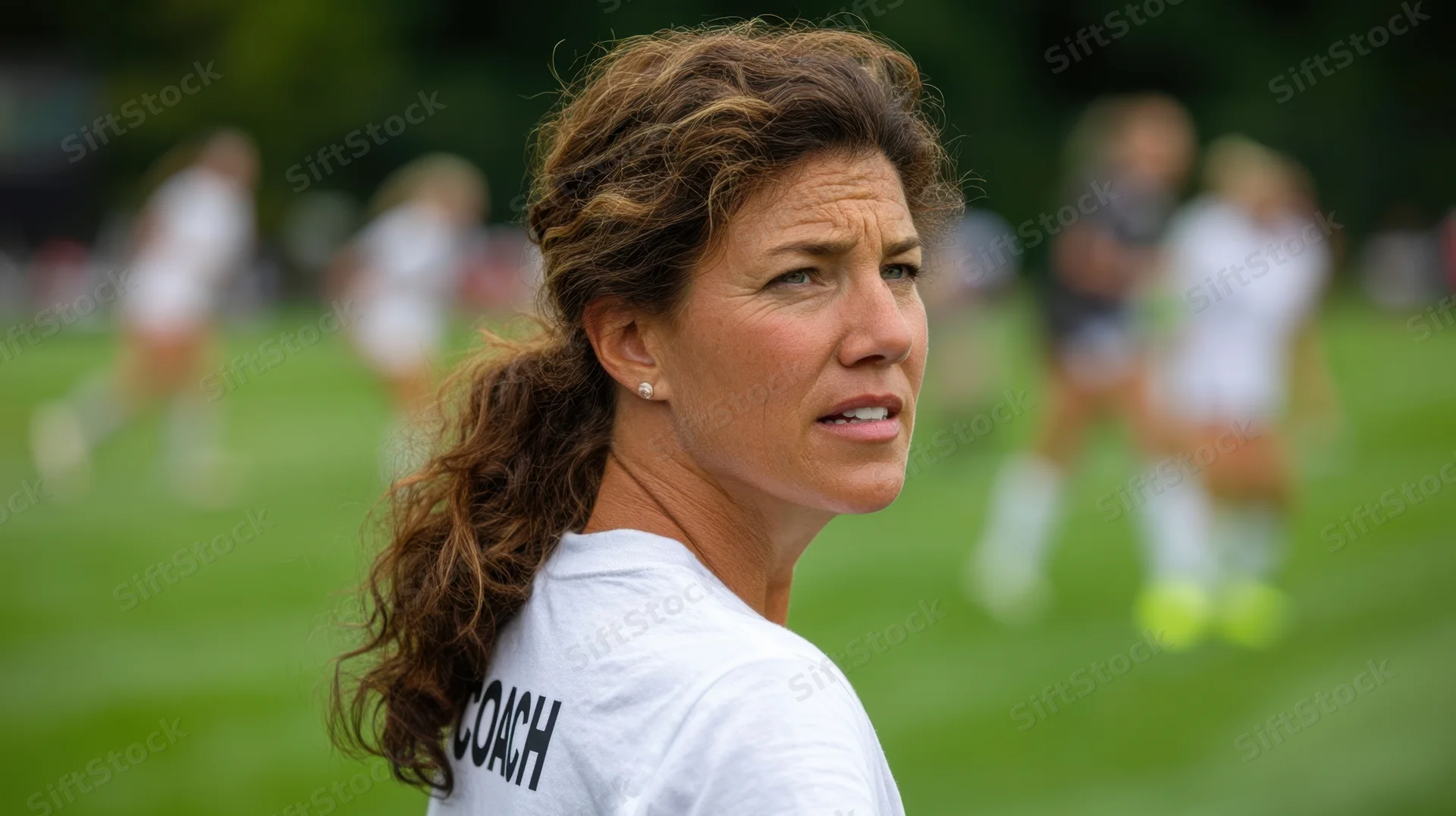 Woman coach observing soccer game on outdoor field
