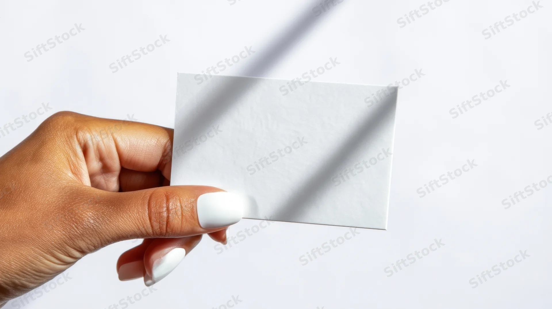 Hand holding a blank white business card against a plain white background