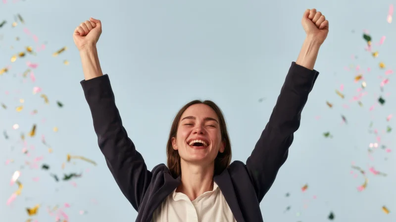 Woman raising arms in celebration with confetti falling around her against a light blue background