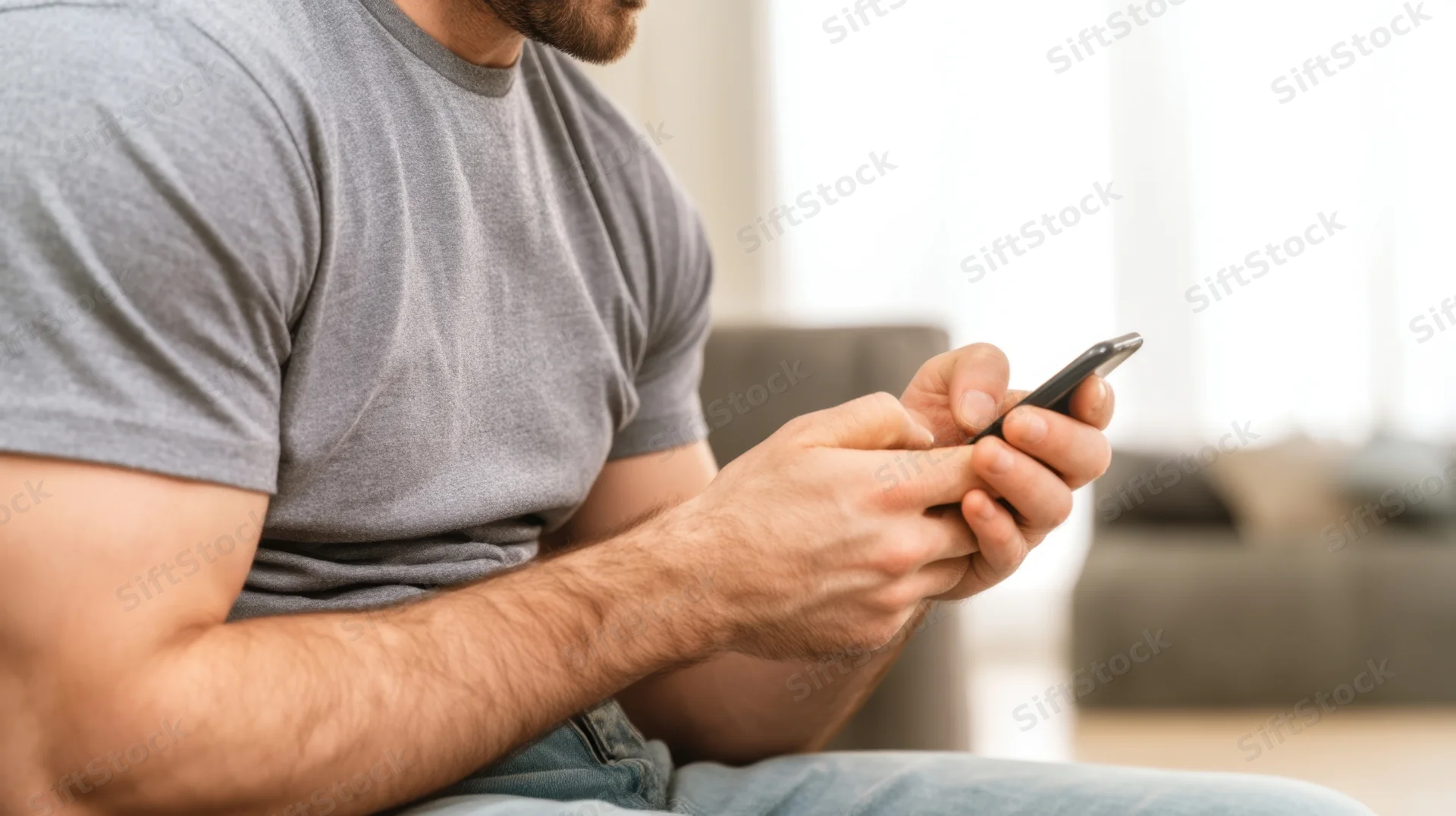 Man texting on smartphone while sitting on couch at home