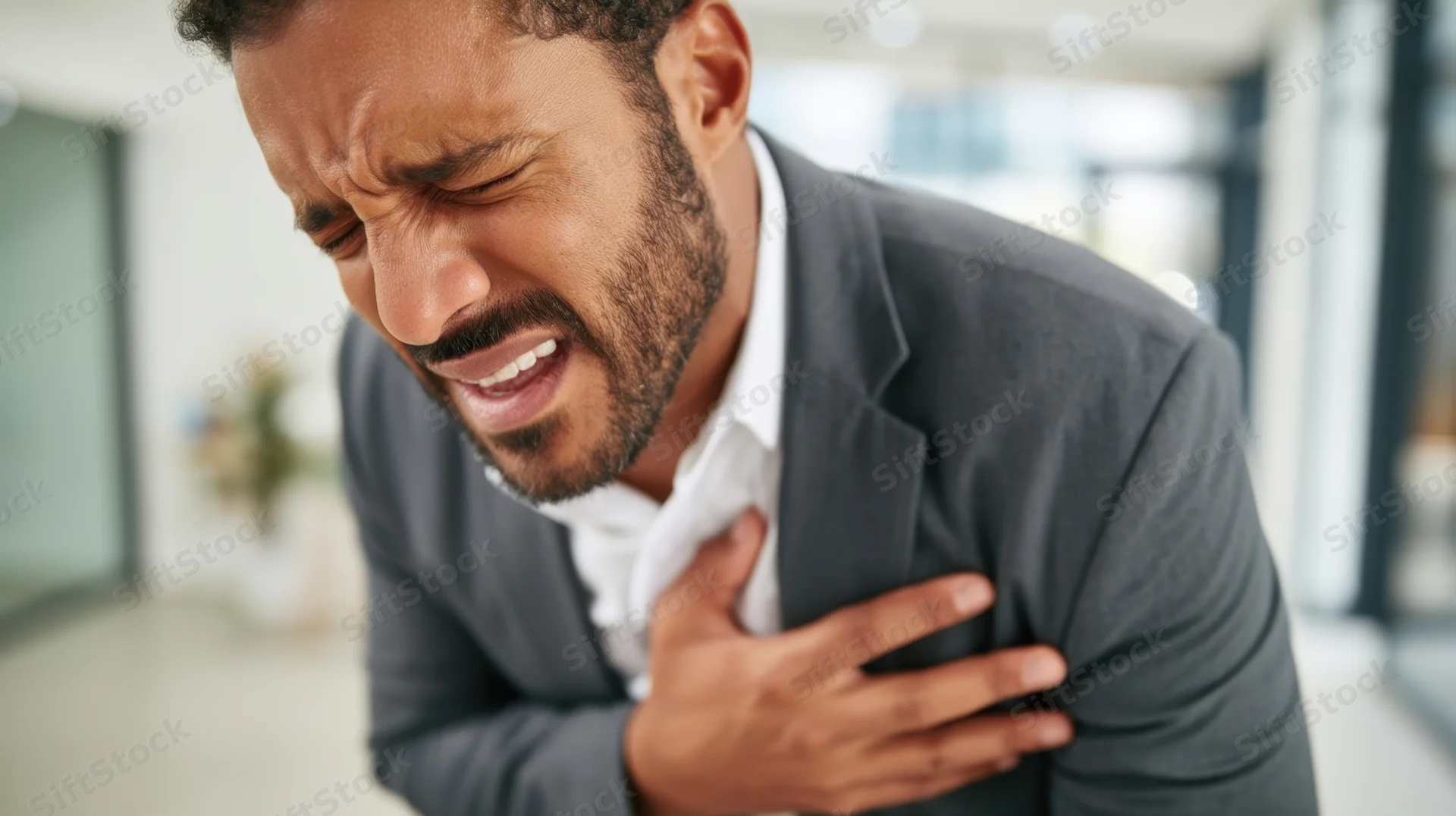 Man clutching his chest in pain in an office setting