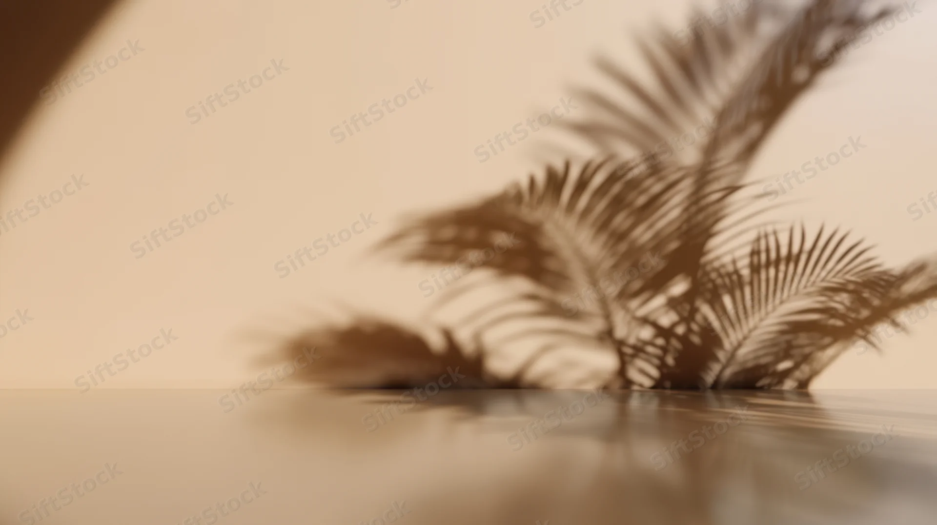 Shadow of palm leaves cast on a beige wall and reflective surface in a minimalist interior