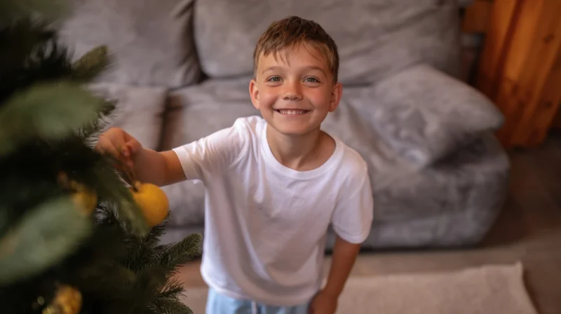 Young boy smiling while decorating a christmas tree in a cozy living room
