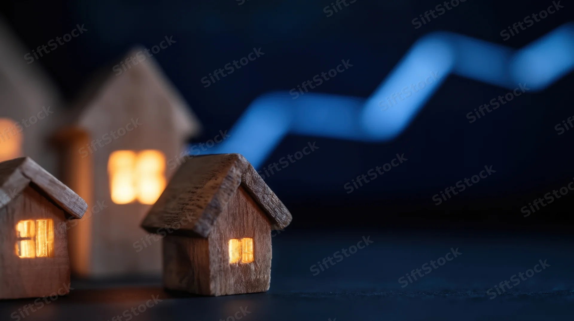 Miniature wooden houses with glowing windows arranged in front of a blue upward-trending graph on a dark surface